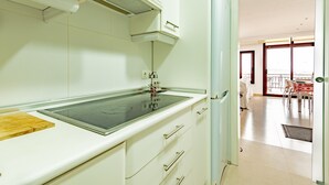 A modern kitchen with a built-in stove, white cabinetry, and a view of the dining area.