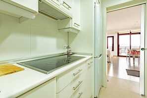 A modern kitchen with a built-in stove, white cabinetry, and a view of the dining area. - 'Apartment Rafael' with Sea View, Terrace & Wi-Fi (Port de Pollença)