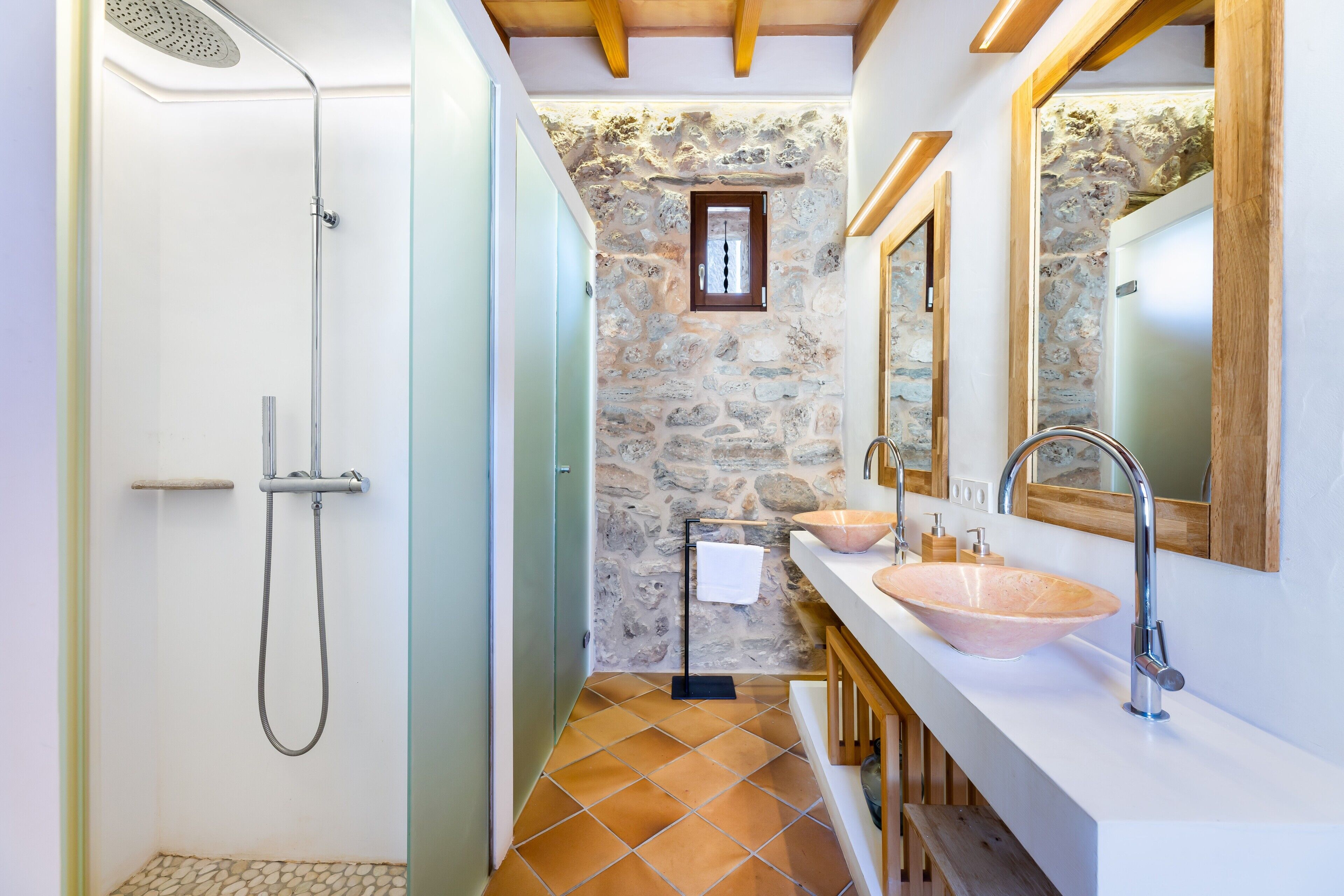A bathroom with a shower, a sink with a stone basin, and a mirror above the sink.