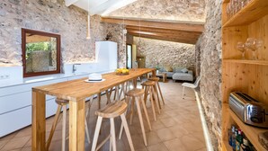 Una cocina rústica con paredes de piedra, taburetes de bar de madera, una mesa de comedor de madera y un tostador empotrado.