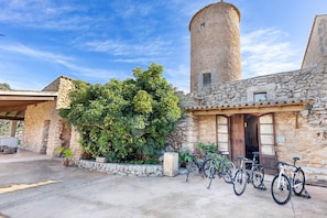A stone building with a tower, a covered patio, and bicycles parked outside.