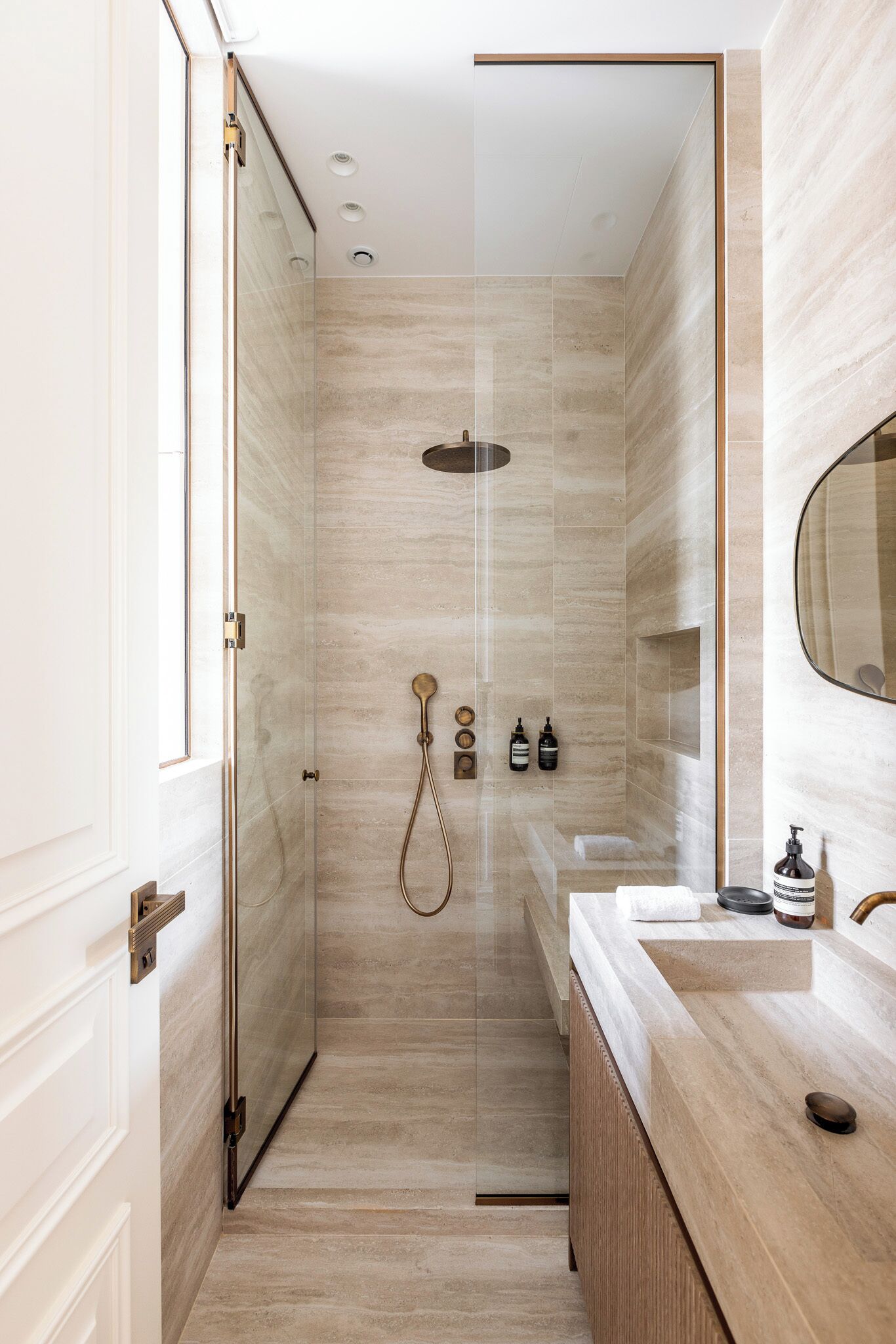 A modern bathroom with a glass shower enclosure, a wooden vanity, and a large mirror.