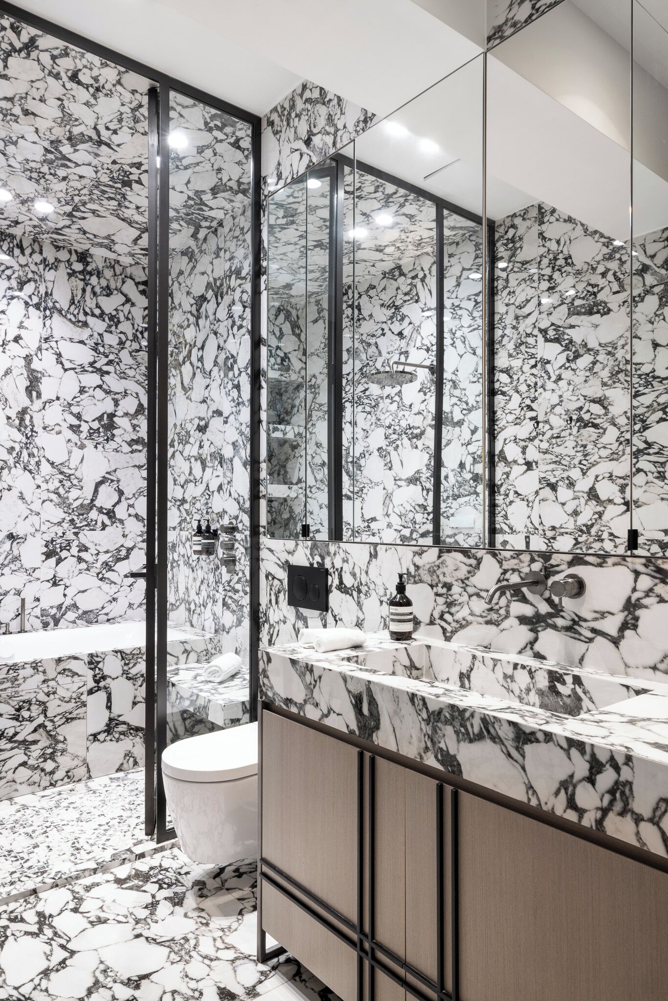 A bathroom with a marble backsplash, a large mirror, and a modern sink.