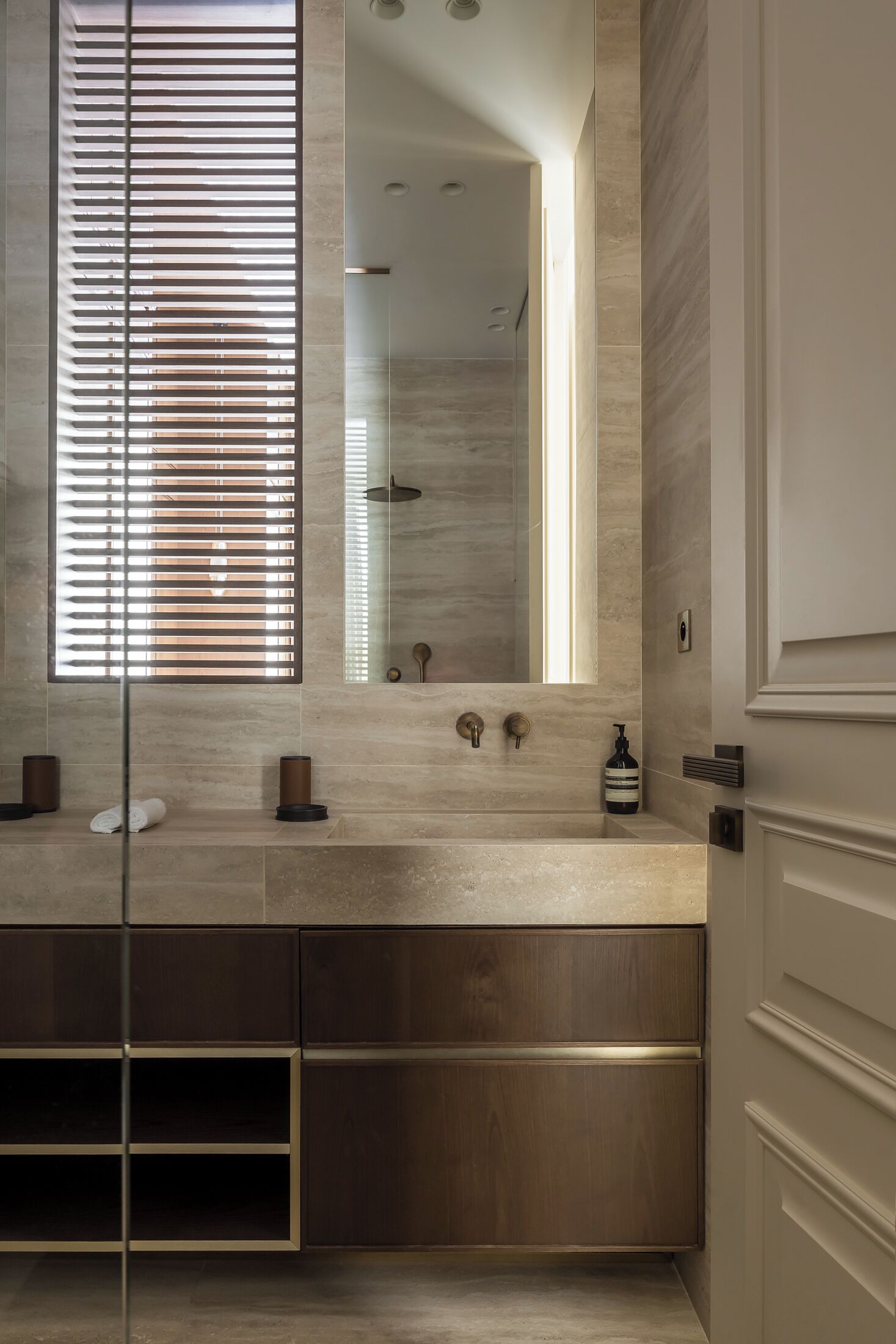 A modern bathroom with a large mirror, a double sink, and a built-in cabinet.