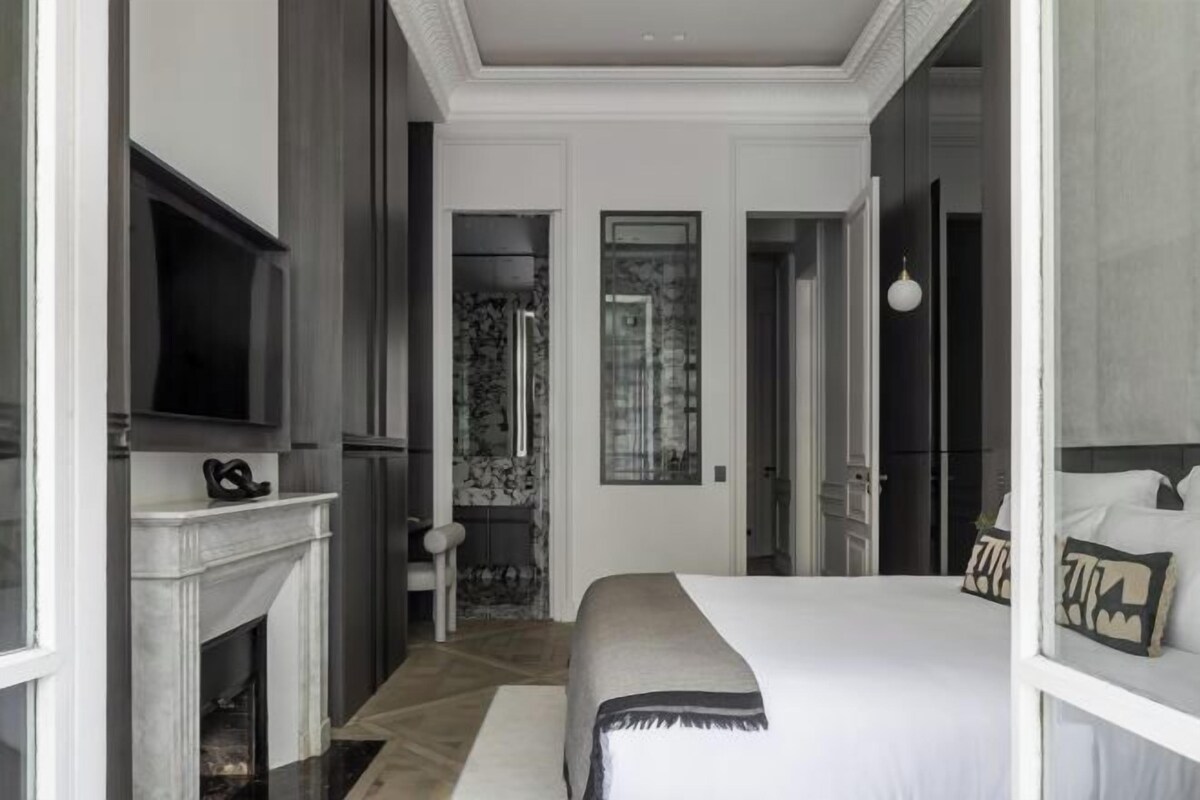 A modern bedroom with a large bed, a fireplace, and a television.