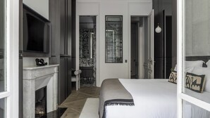 Et moderne hotelværelse med en stor seng, pejs, fjernsyn og badeværelse med bruser og spejl.