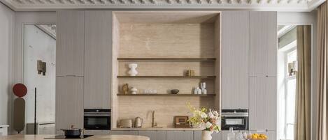 A modern kitchen with a central island, built-in shelves, and a dining area with chairs.