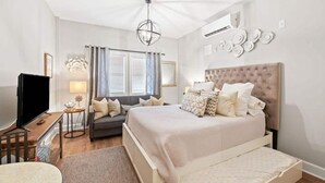 Een moderne slaapkamer met een groot bed, een televisie, een bank en een bureau met een lamp.