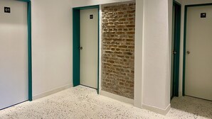 A hallway with three doors, each marked with a number. The walls are white, and the floor is speckled.
