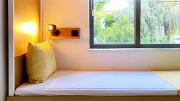 A bunk bed with a window, a bedside lamp, and a small shelf.