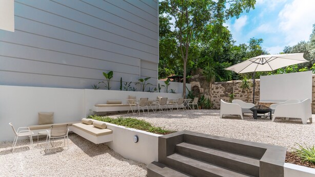 A modern outdoor patio with a seating area, steps, and a small table with an umbrella.