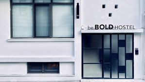 A building facade with a large window and a door with a bold hostel sign.