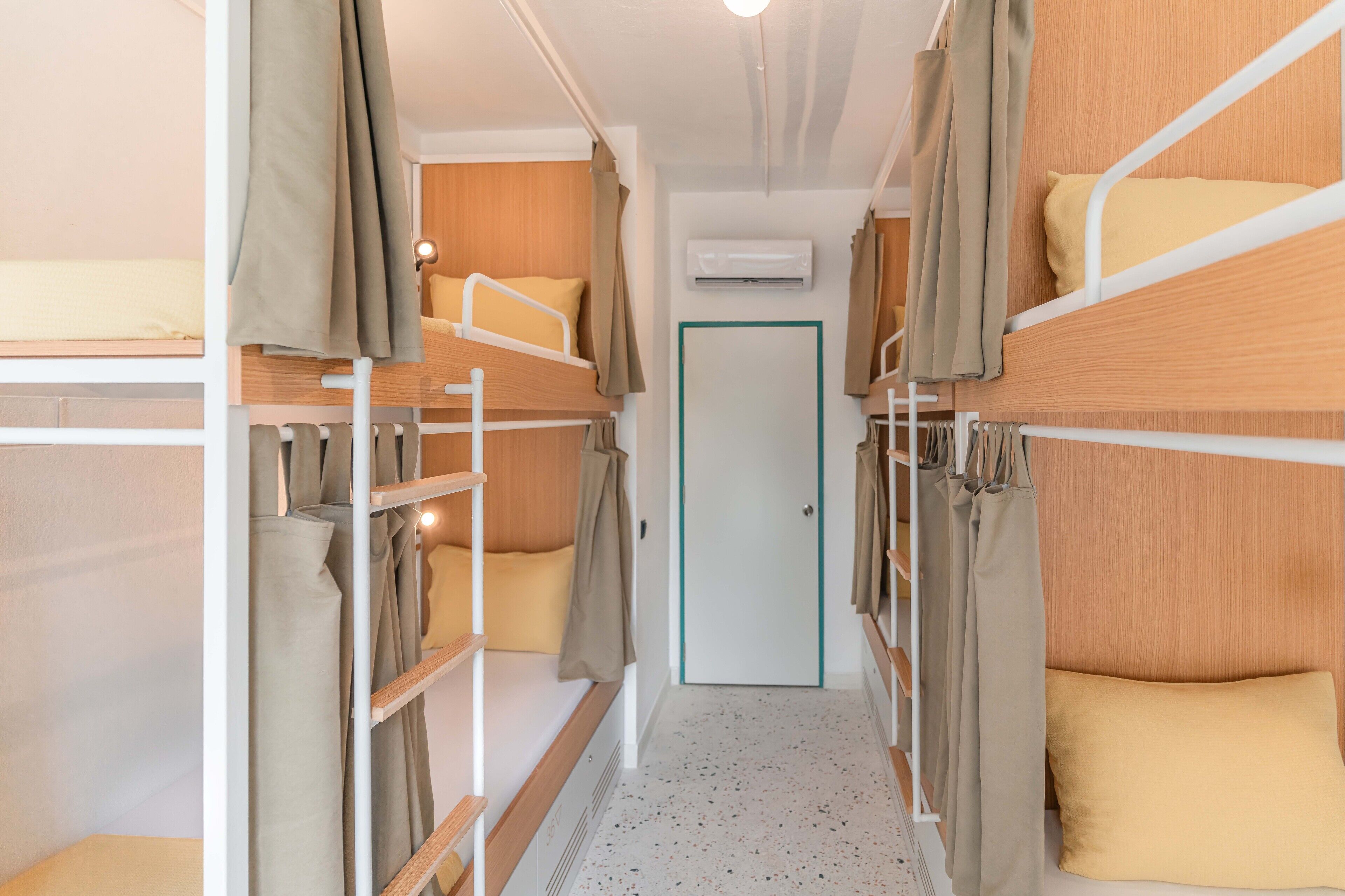 A bunk bed room with a door, air conditioning unit, and a light fixture.