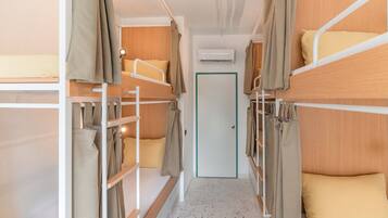 A bunk bed room with a door, air conditioning unit, and a light fixture.