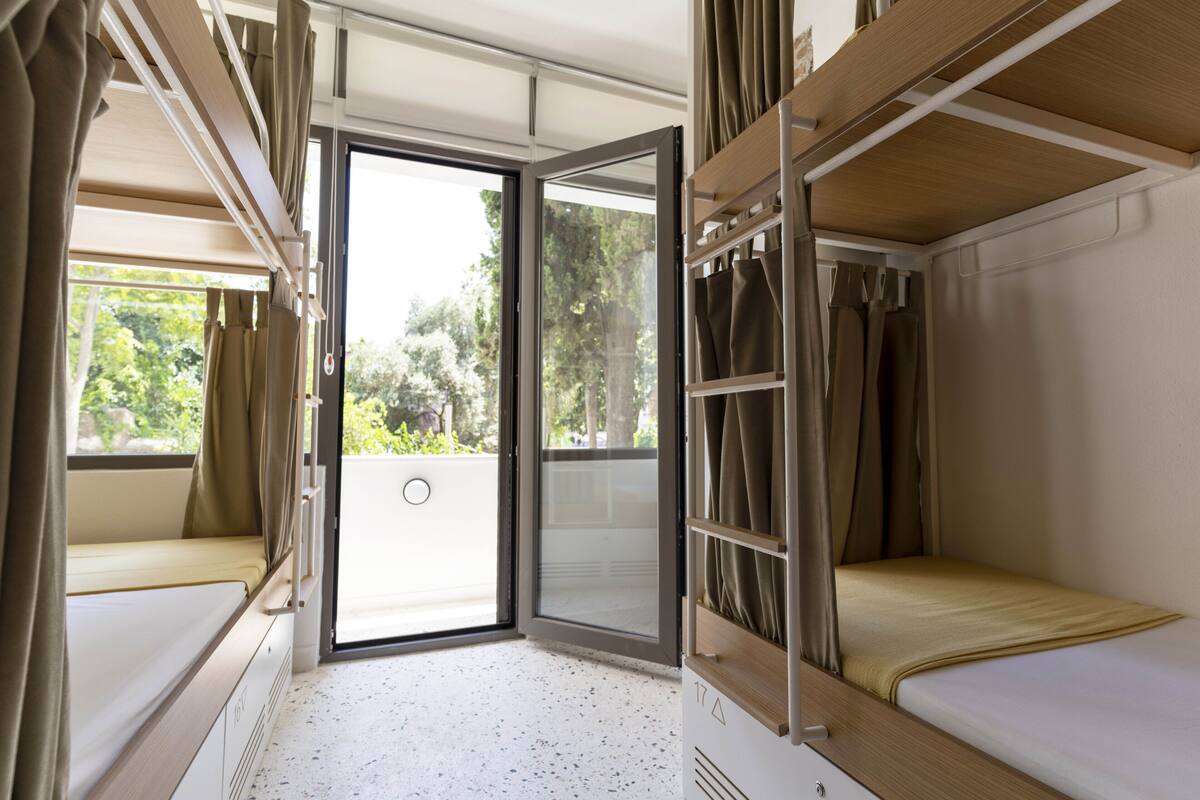 A compact room with a bunk bed, a sliding door to an outdoor area, and a small seating area.