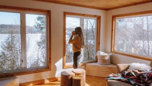 A room with large windows, a wooden ceiling, and a view of a snowy landscape. - Rustic-Luxury Waterfront Cottage Getaway on Kennisis Lake Stunning Elevated View (Haliburton)