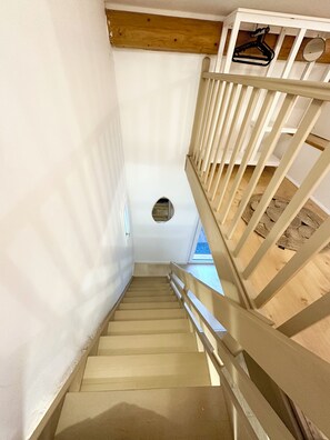 Una escalera de madera con barandas blancas y techo de vigas de madera.