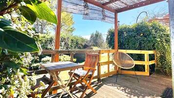 A wooden deck with a pergola, two folding chairs, and a table.