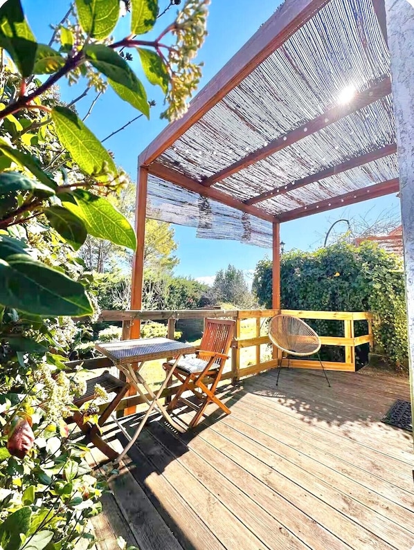 A wooden deck with a pergola, two folding chairs, and a table.