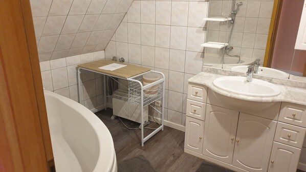 Un baño con bañera, lavamanos, espejo y perchero para toallas.