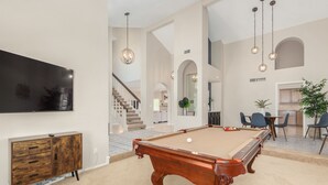 A spacious living room with a pool table, a flat-screen TV mounted on the wall, and a staircase leading to an upper level. - *Great Rates Available* | North Scottsdale Peaceful Paradise (Scottsdale)