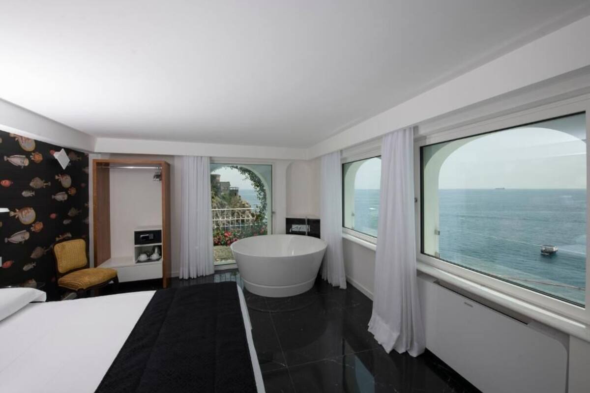 Une chambre d’hôtel moderne avec un grand lit, une baignoire et une vue sur la mer.