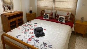 A neatly arranged bedroom with a bed, a wooden nightstand, a dresser, and a mirror. - Larnaca Comfort Rooms (Larnaca)