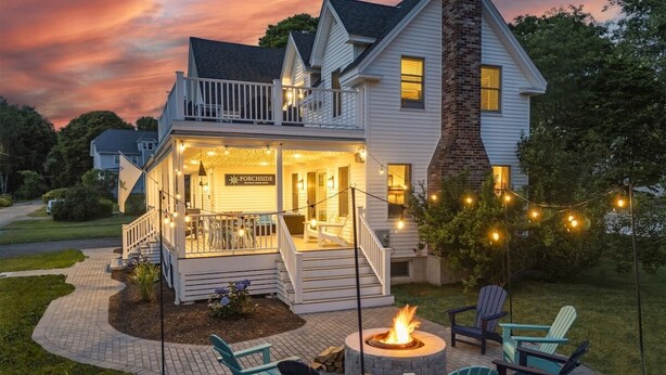 A two-story house with a porch, outdoor seating, and a fire pit.