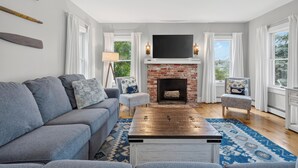 A living room with a sofa, armchairs, a fireplace, and a TV.