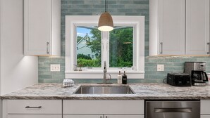 A kitchen with a window, a sink, a toaster, and a coffee maker.