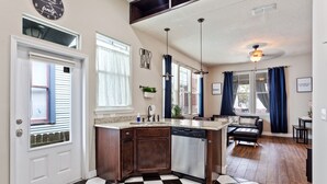 Une cuisine avec un carrelage à motifs, des meubles en bois, un lave-vaisselle et un coin repas comprenant un canapé et une table.