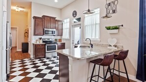 Une cuisine moderne avec un carrelage à motifs, des meubles en bois, un îlot central doté de tabourets, un four à micro-ondes et un évier.