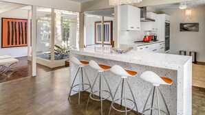 Een moderne keuken met een groot eiland, barkrukken en uitzicht op de omgeving.