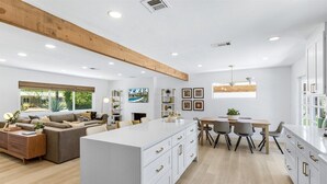 Un vaste espace de vie comprenant un grand îlot central, une table à manger et un coin cuisine.