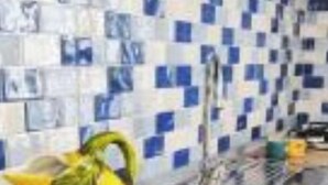 Una cuina amb un rebedor de rajola i una tetera groga damunt el taulell.