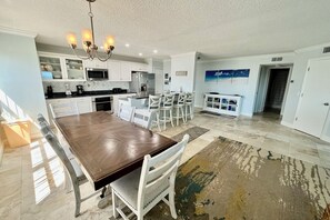 A spacious kitchen with a large island, white cabinetry, and a dining area with white chairs. - FREE FUN INCLUDED DAILY, beautiful Ocean Front 3rd floor condo with unbeatable views! (Saint Augustine)