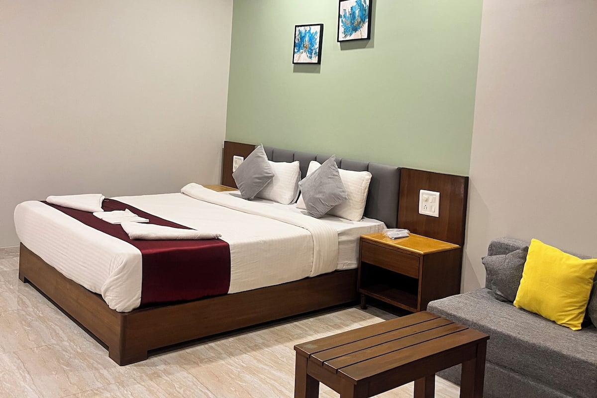 Una habitación de hotel con cama, mesita de noche y un banco de madera.