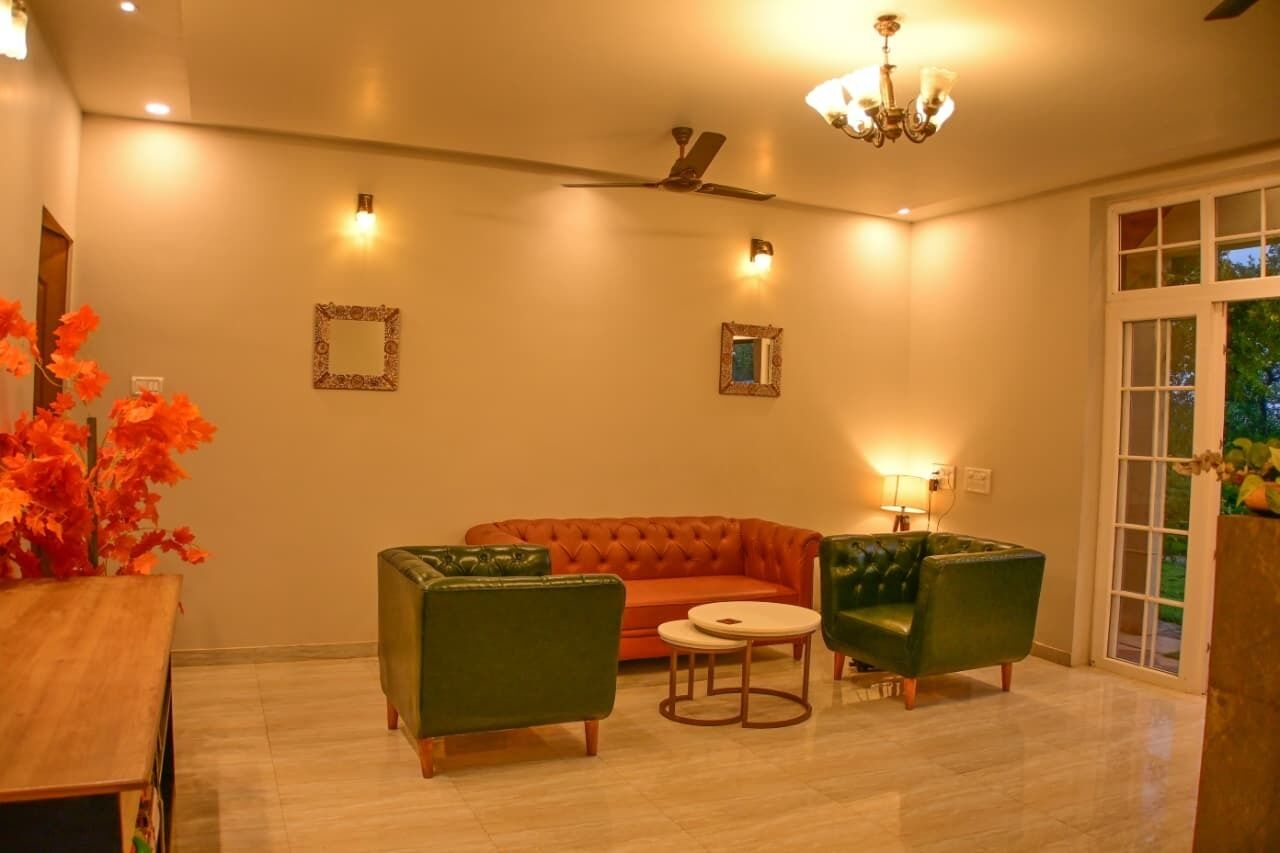 Un salon comprenant un canapé, deux fauteuils, une petite table et un ventilateur de plafond.