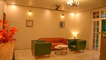 Un salon comprenant un canapé, deux fauteuils, une petite table et un ventilateur de plafond.