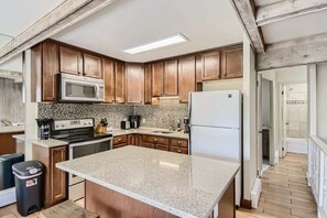 A kitchen with wooden cabinets, a microwave, stove, and a refrigerator. - Amazing Lake and Mountain Views! (Dillon)
