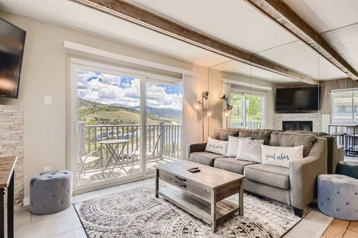 Ein geräumiges Wohnzimmer mit großen Schiebeglasfenstern zum Balkon, einer Couch mit Zierkissen, einem Couchtisch und einem flachbildfernseher an der Wand.