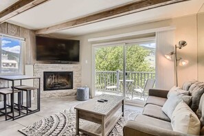 A living room with a fireplace, a sofa, a coffee table, and a TV. - Amazing Lake and Mountain Views! (Dillon)