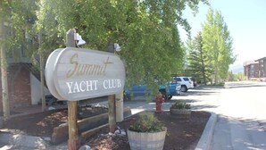 Schild des Summit Yacht Club, umgeben von Bäumen und einer gepflegten Grünfläche mit Pflanzgefäßen.