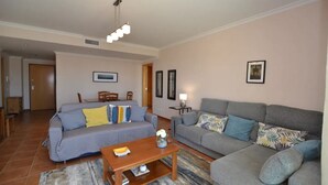A living room with two sofas, a coffee table, and a lamp. There is a door leading to another room and a framed picture on the wall. - Magnolia - Beach & Pool - Fantastic T2 (Albufeira)
