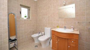 A bathroom with beige tiled walls, a white sink, a mirror, a bidet, and a toilet. - Magnolia - Beach & Pool - Fantastic T2 (Albufeira)