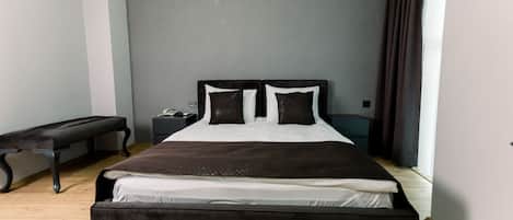 A modern bedroom with a large bed, a bench, and a nightstand.