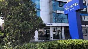 En modern hotellbyggnad med en väl synlig skylt som visar texten ”TRIO HOTEL airport”.