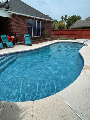 A swimming pool with clear blue water, surrounded by a brick house and a red fence. - 🏊‍♀️ Swimming 🏊‍♂️ Pool & 🏀Basketball Court washer and dryer, 4 tvs.  Great place come (McAllen)