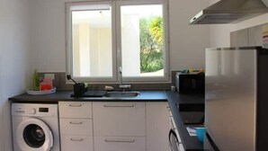 Una cucina moderna con lavatrice integrata, un'ampia finestra e un frigorifero in acciaio inossidabile.