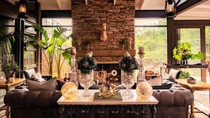 A cozy living room with a stone fireplace, leather sofa, and decorative glass vases. - Safari Moon Luxury Bush Lodge (Hoedspruit)